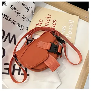 Dettaglio di una mini borsa a tracolla arancione in nylon con fibbia e cinturino regolabile