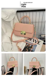 Detail of light pink crossbody bag featuring a twisted handle and gold square clasp