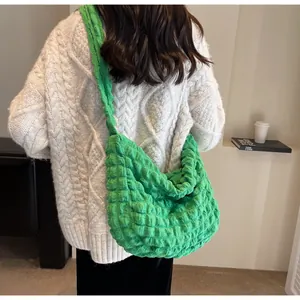 Détail du sac à bandoulière vert en tissu popcorn avec plis et large lanière