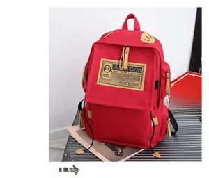 Dettaglio macro zaino in tela rossa con etichetta vintage su una valigia grigia