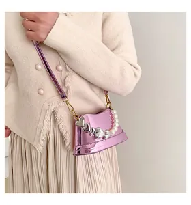 Dettaglio della mini borsa a secchiello rosa metallizzata con perle e cuori pendenti