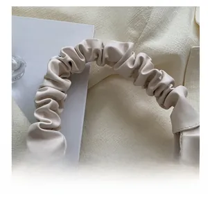 Close-up of ruched handle detail on cream PU leather shoulder bag with fine stitching