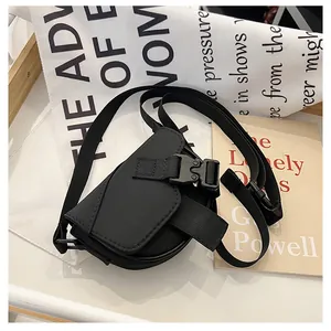 Dettaglio di una mini borsa a tracolla in nylon nero con fibbia tattica su vassoio bianco