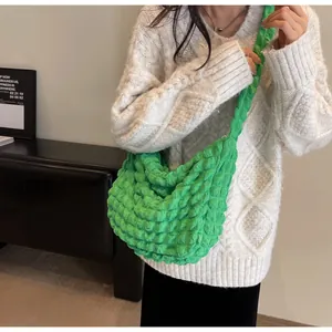 Détail du tissu texturé pop-corn vert vif sur un sac à bandoulière en demi-lune