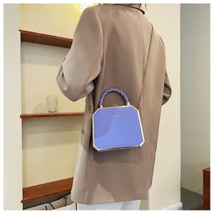 Detail of blue acrylic shell box bag with gold metal frame and woven top handle