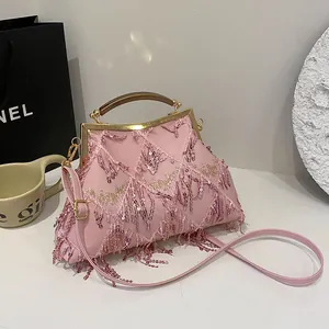 Dettaglio borsa da sera rosa con paillettes, manico dorato e trama a griglia con nappe