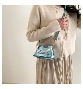Dettaglio mini borsa a secchiello in vernice blu con manico in perle e fibbia a cuore