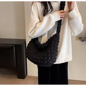 Détail du tissu à texture pop-corn noire et design plissé d'un sac demi-lune