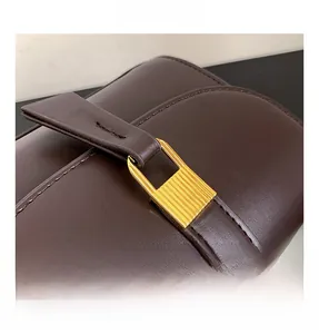 Macro view of vintage dark brown leather bag showing a golden metal lock with textures