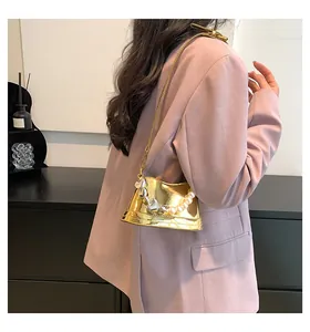 Dettaglio della mini borsa a secchiello dorata con tracolla di perle e ciondolo a cuore