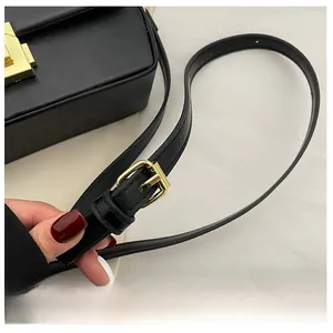 Detail of adjustable black leather shoulder strap with a golden square metal buckle