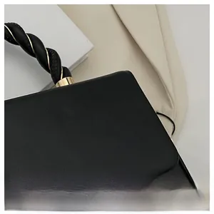 Detail of black leather handbag featuring a knotted handle and gold metal twist lock