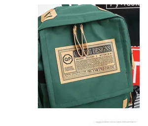 Dettaglio dello zaino in tela verde scuro con toppa in pelle vintage e doppia cerniera
