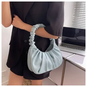 Close-up of light blue ruched crescent underarm bag in a modern office setting