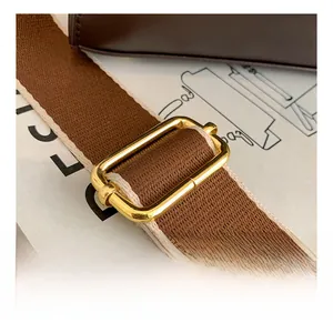 Detail of adjustable brown fabric shoulder strap with premium gold metal buckle and stitching