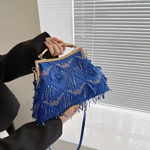 Dettaglio borsa da sera con paillettes blu reale, manico in metallo dorato e trama di lusso