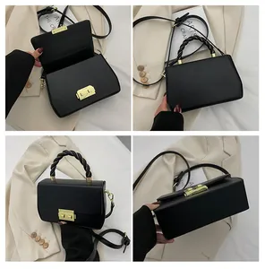 Detail of black structured bag featuring a woven leather handle and gold metal buckle