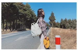Scatto all'aperto di uno zaino in tela bianco panna con scomparto principale e tasche frontali