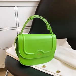 Borsa a tracolla semicircolare verde vibrante con tracolla regolabile su sedia