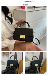 Detail of black crossbody bag with woven black and gold handle and metallic gold twist lock