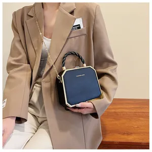 Detail showing octagonal black hard shell purse with gold metal frame and woven handle