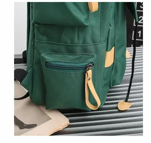 Dettaglio dello zaino verde con tasca laterale a zip e accenti in finta pelle