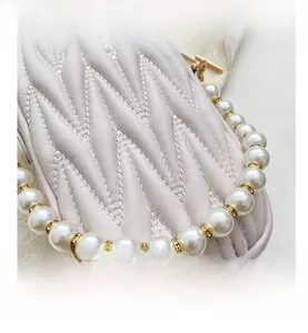 Detail of beige quilted bag with elegant faux pearl handle and crystal spacers