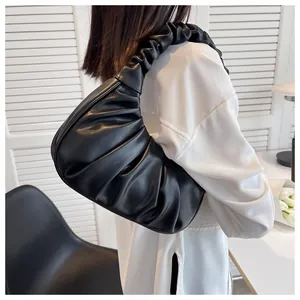 Close-up of black pleated cloud bag on shoulder featuring stylish ruched strap detail