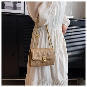 Dettaglio borsa a tracolla trapuntata beige con catena dorata e chiusura quadrata