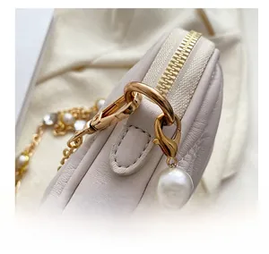 Detail of lychee pattern leather handbag with gold zipper and pearl chain hook