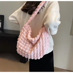 Sac à bandoulière rose à texture bulles porté par un mannequin au style tendance