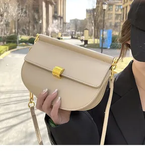 Dettaglio di una borsa a sella in pelle opaca beige con chiusura quadrata in oro