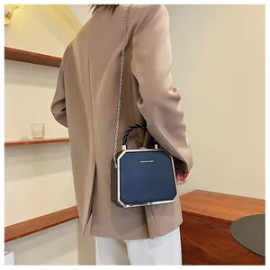 Detail view of dark blue structured hard case bag with metal chain strap and gold edges