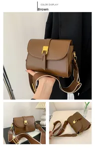 Detail of brown vintage shoulder bag with golden square lock and adjustable wide strap