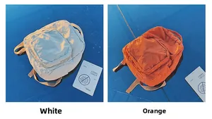 Dettaglio degli zaini in tela lavata in bianco e arancione con spallacci regolabili