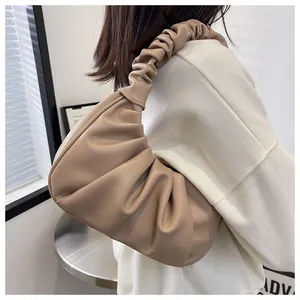 Detail of beige pleated crescent underarm bag showing soft PU leather texture on shoulder