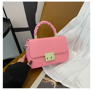 Detail of pink crossbody bag with woven handle and gold square metallic lock