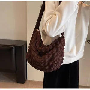 Détails de la texture plissée marron du sac à bandoulière hobo porté par le mannequin