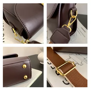 Detail view of dark brown leather bag with golden hooks and woven shoulder strap