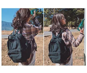 Dettaglio laterale di uno zaino vintage in tela nera su una modella all'aperto