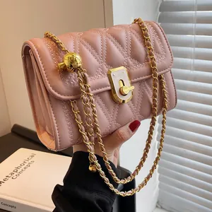 Borsa a tracolla rosa trapuntata con catena dorata e ciondolo a sfera tenuta da una modella