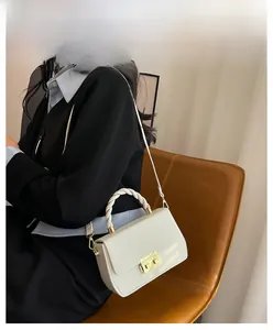 Elegant ivory faux leather crossbody bag with a unique braided handle and gold hardware detail