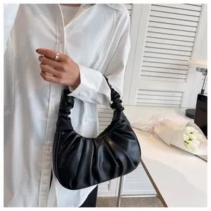 Detail view of black pleated moon-shaped underarm bag with matte faux leather texture
