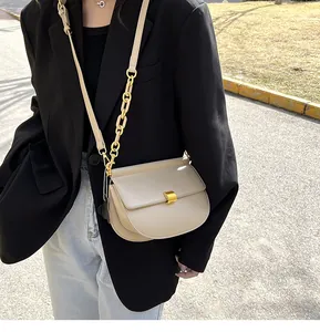 Dettaglio borsa a sella beige con chiusura dorata quadrata e tracolla in pelle e catena