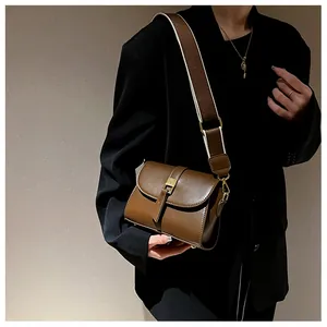 Detail of dark brown vintage leather crossbody bag with golden buckle and wide strap