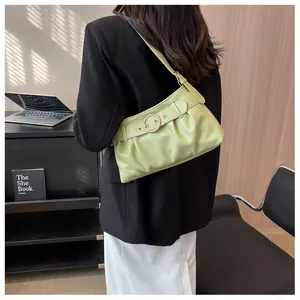 Dettaglio della borsa a spalla plissettata verde chiaro con fibbia dorata sulla modella