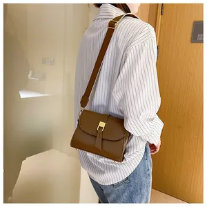 Close-up of a vintage brown leather crossbody bag with a gold buckle and tassel detail