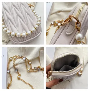 Close-up of quilted cream phone bag with pearl handle and golden chain strap details