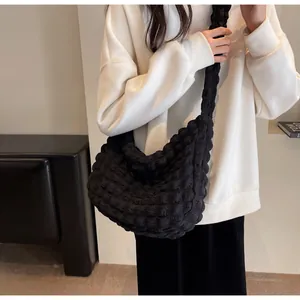 Sac croissant noir à texture bulle avec bandoulière plissée porté par un mannequin