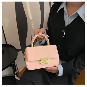Detail of pink faux leather bag with woven rope handle and gold metal square lock